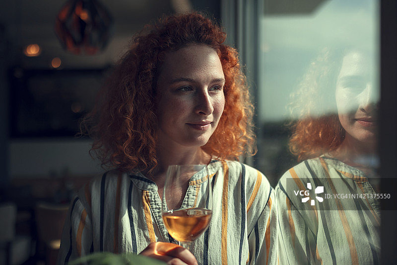 喝白葡萄酒的年轻红发女子图片素材