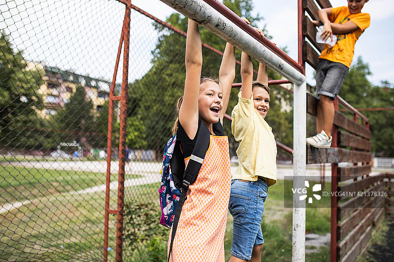课间休息时挂在球门柱上的学龄儿童图片素材