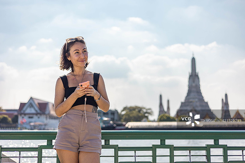 年轻女游客在曼谷市区用手机拍照图片素材