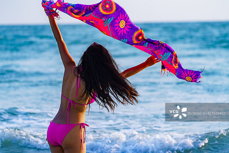 美丽年轻女人戴墨镜在海滩跑步图片素材