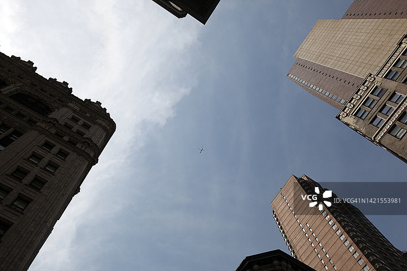 低角度的看法，一个遥远的直升机飞越摩天大楼，曼哈顿，纽约，美国图片素材