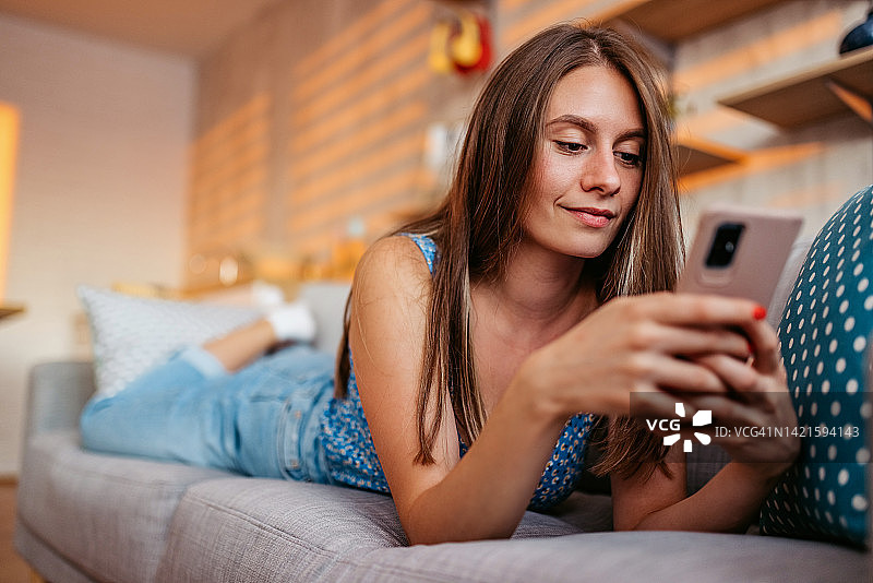 年轻女人在家中使用智能手机查看社交媒体图片素材