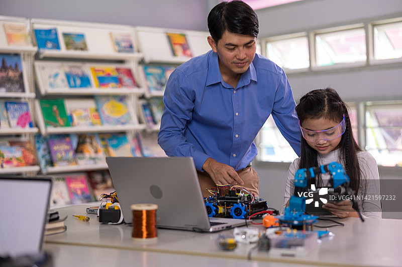 亚洲男教师在课堂上帮助青少年学生制作汽车模型机器人图片素材
