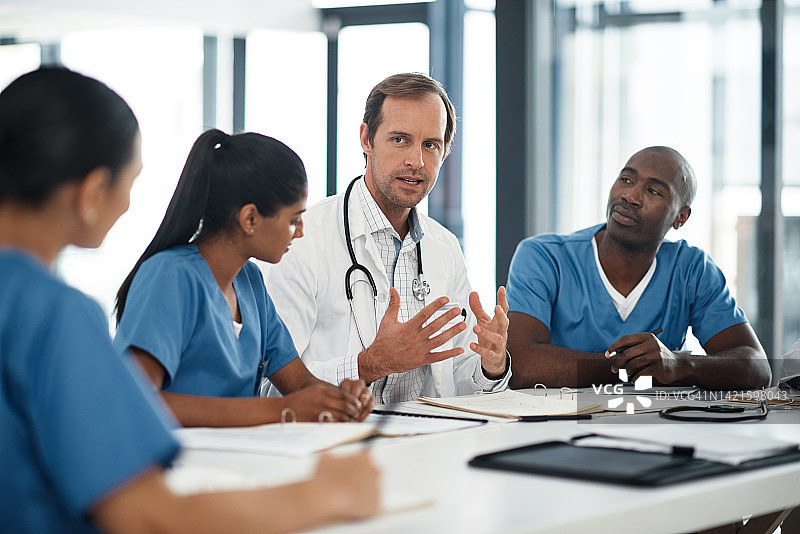 医生与护士团队交谈，医疗保健专业人员在医疗会议室办公室开会。男医生谈论医院工作，世界卫生日交流和人们一起工作图片素材
