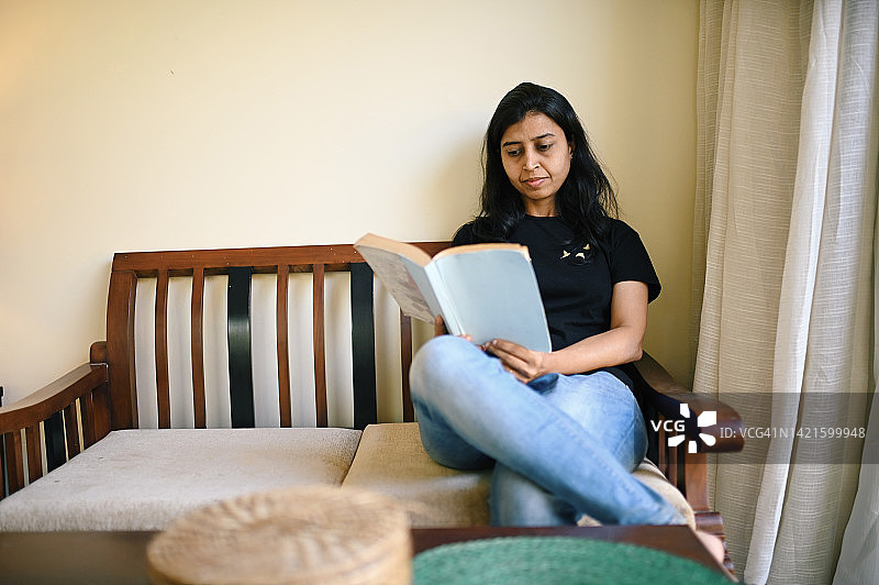 女人坐在木沙发上看书图片素材