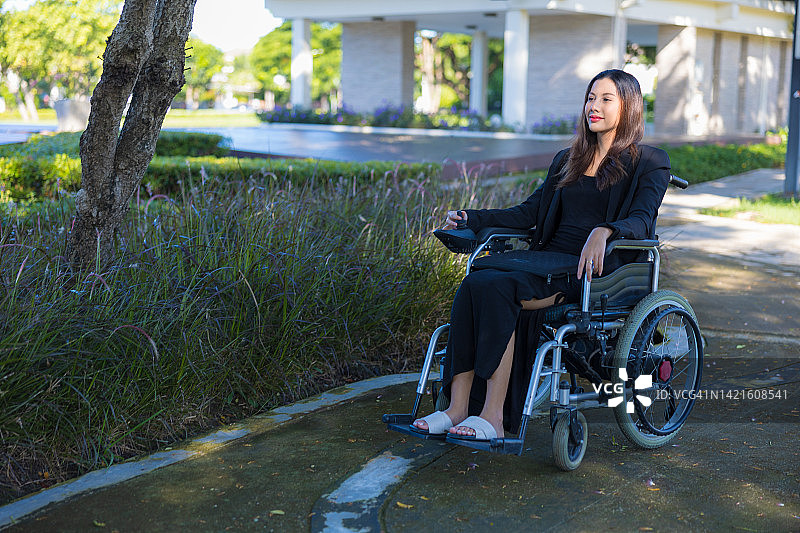 亚洲女性在公园里使用电动轮椅图片素材
