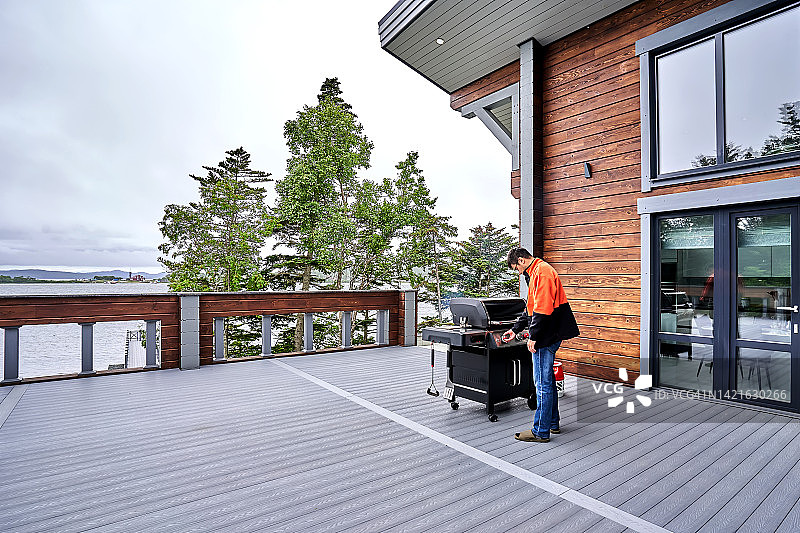 在木屋露台上烧烤的亚洲男人图片素材