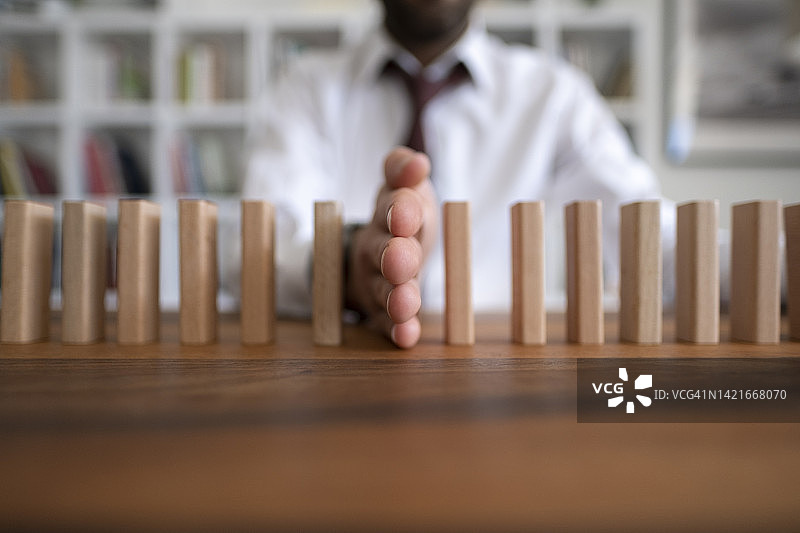 商人阻止多米诺骨牌效应：风险管理和保险概念图片素材