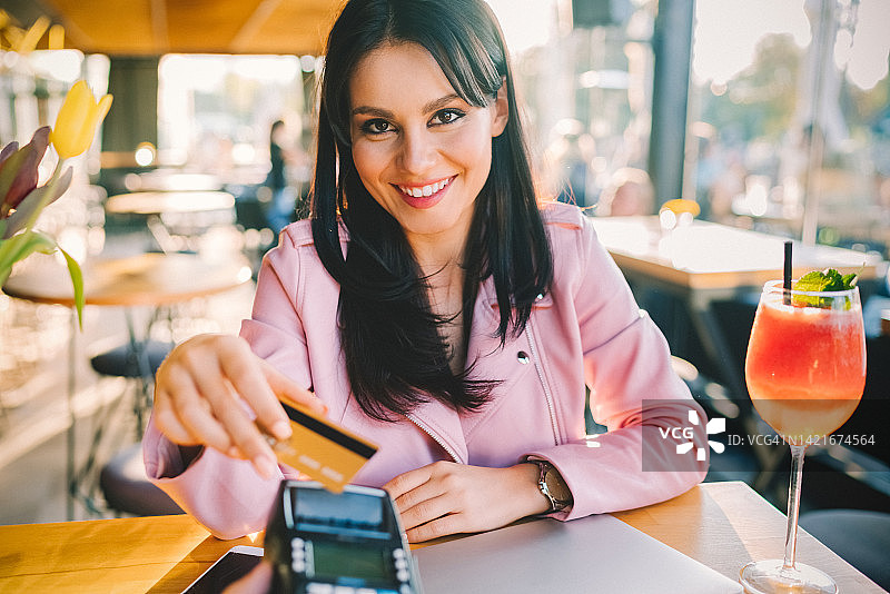 年轻女人在咖啡馆用信用卡进行非接触式支付图片素材