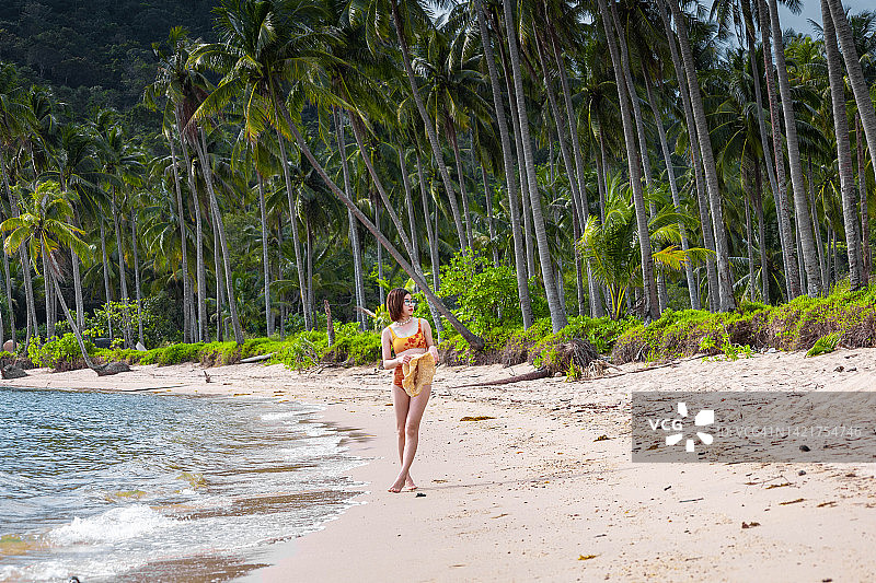 年轻女子站在泰国象岛的海边，眺望棕榈树图片素材