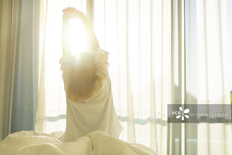 清晨，穿着睡衣伸懒腰的女人图片素材