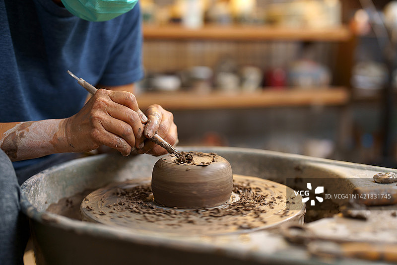 女性手部特写：在陶器上雕刻陶瓷花纹图片素材