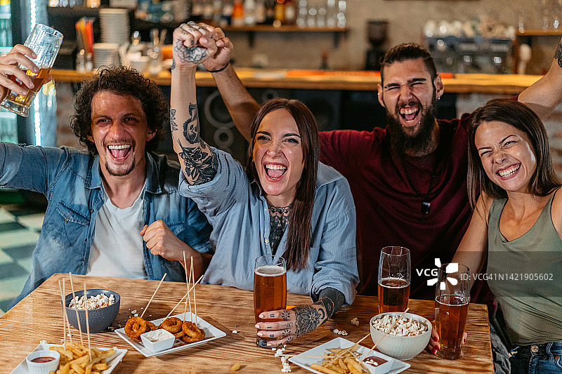 一群朋友在酒吧观看体育比赛并为他们的球队加油图片素材