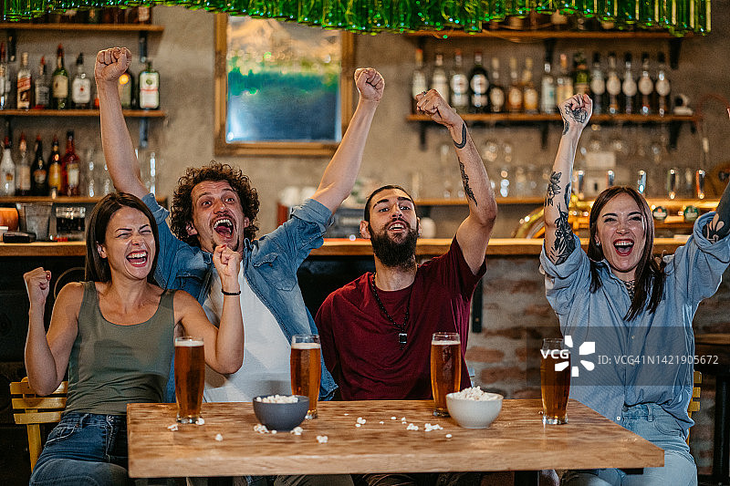 一群朋友在酒吧观看体育比赛并为他们的球队加油图片素材