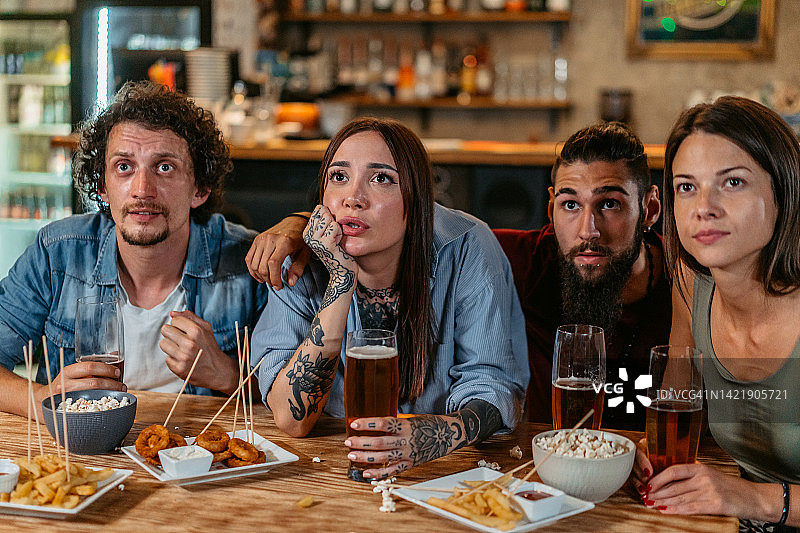 一群朋友在酒吧观看体育比赛并为他们的球队加油图片素材