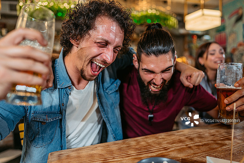 一群朋友在酒吧观看体育比赛并为他们的球队加油图片素材