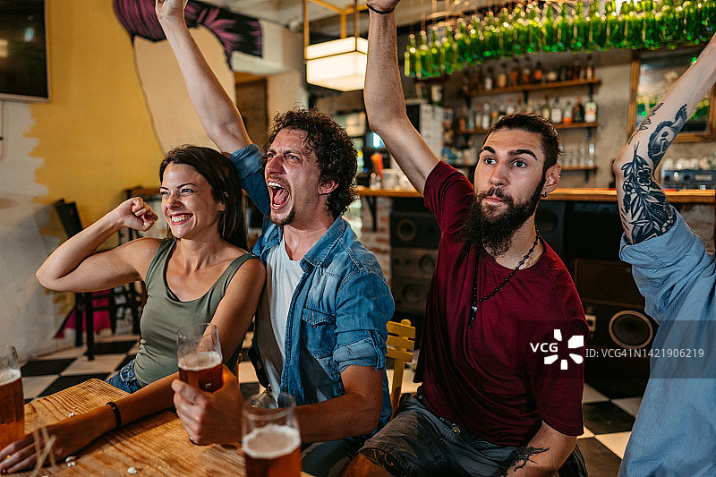 一群朋友在酒吧观看体育比赛并为他们的球队加油图片素材