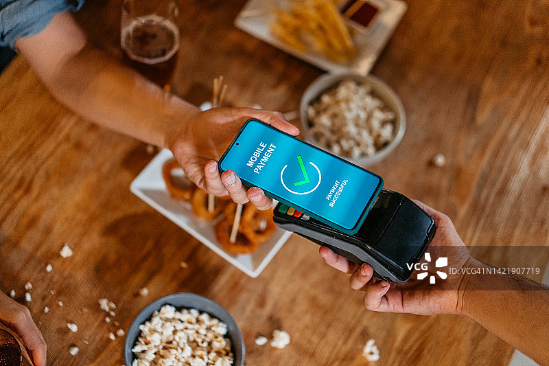 年轻男人通过手机银行App进行非接触式支付图片素材