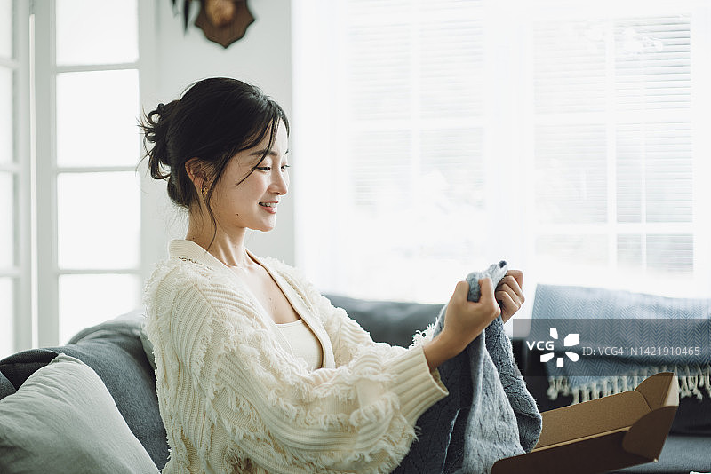 漂亮的亚洲女人打开朋友送的礼物图片素材