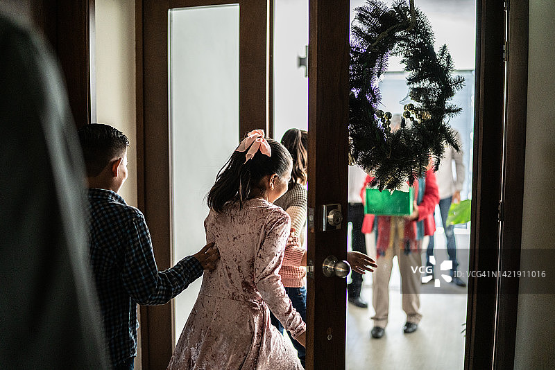 孩子们打开门欢迎家人回家过圣诞节图片素材