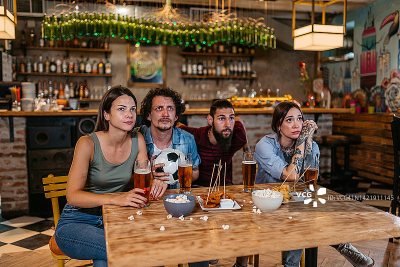 朋友们在酒吧观看足球比赛并为他们的球队加油图片素材