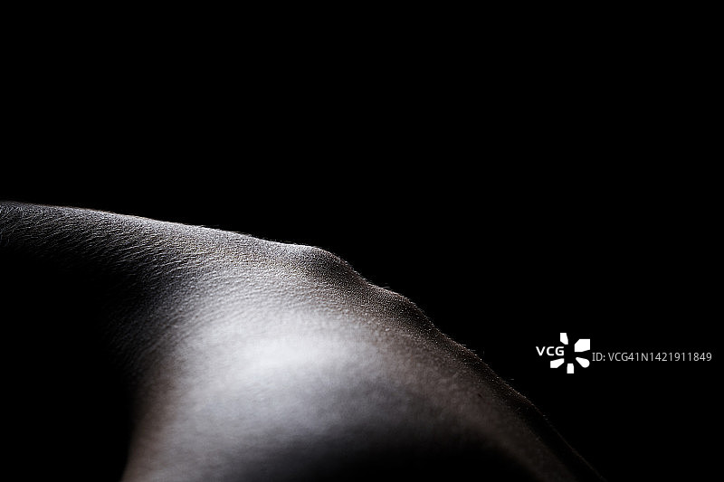 日本年轻女子侧面像，头部前倾。脊椎骨骼强烈突出，在黑色孤立背景上形成美丽的图案。现代艺术、颈椎骨软骨病、颈部和背部疼痛概念图片素材