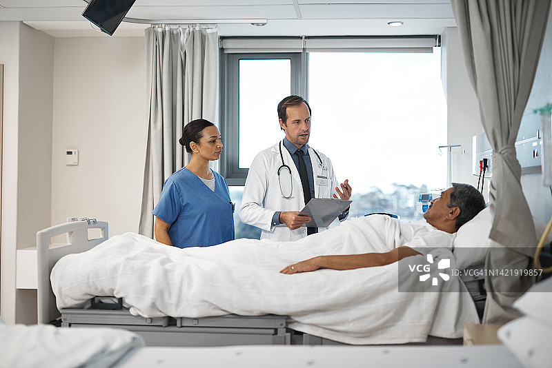 人寿保险：医生和护士在病床旁咨询癌症患者，提供帮助、支持和服务。医护人员告知老人血液检测结果图片素材
