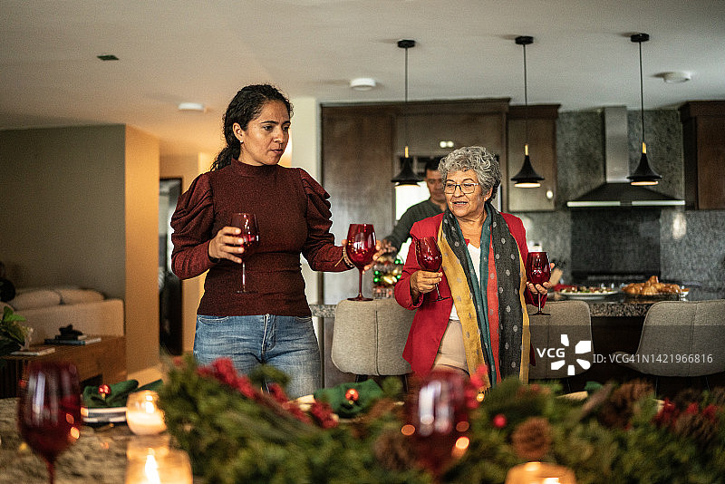 中年妇女在家帮忙母亲准备圣诞餐桌时交谈图片素材