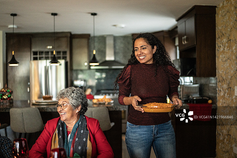 女儿在家中给餐桌上的年长母亲端来红薯泥图片素材