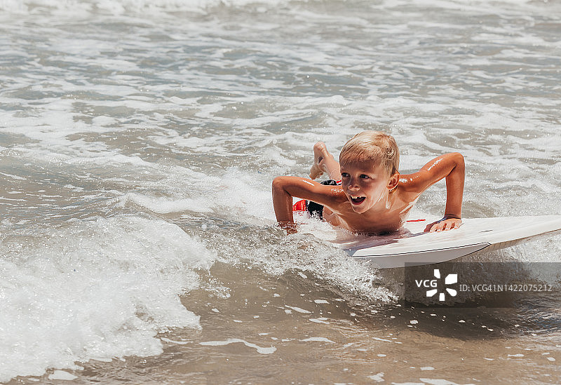 在热带水域玩漂流板的男孩图片素材