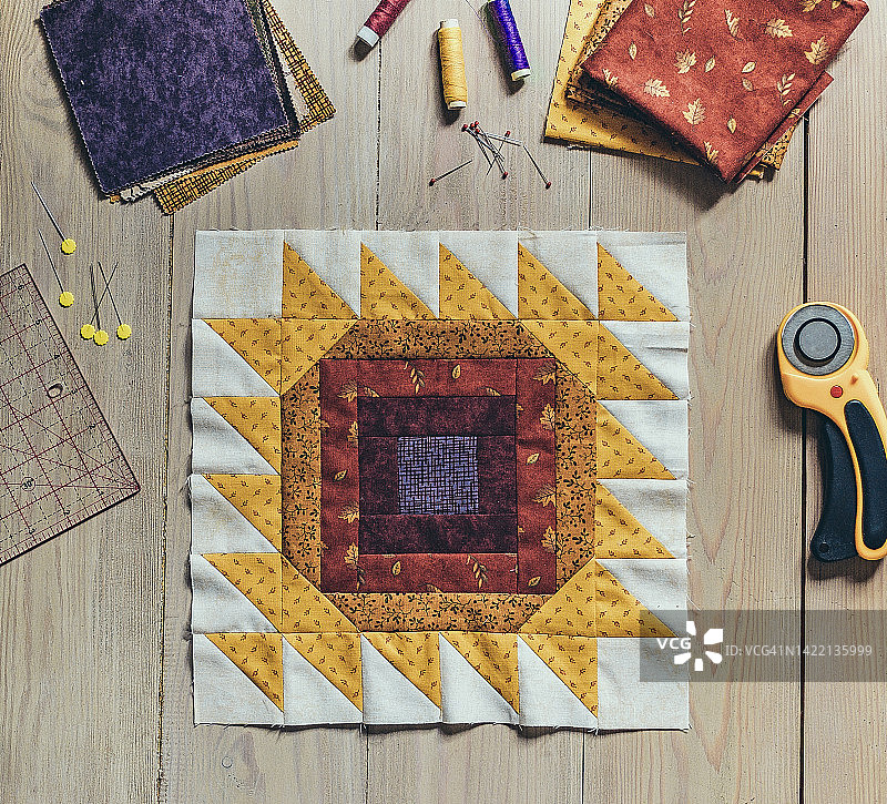 绗缝缝纫配件，拼布向日葵夏秋块状被子碎片，拼布红黄块状被子，木制背景上的缝纫配件图片素材