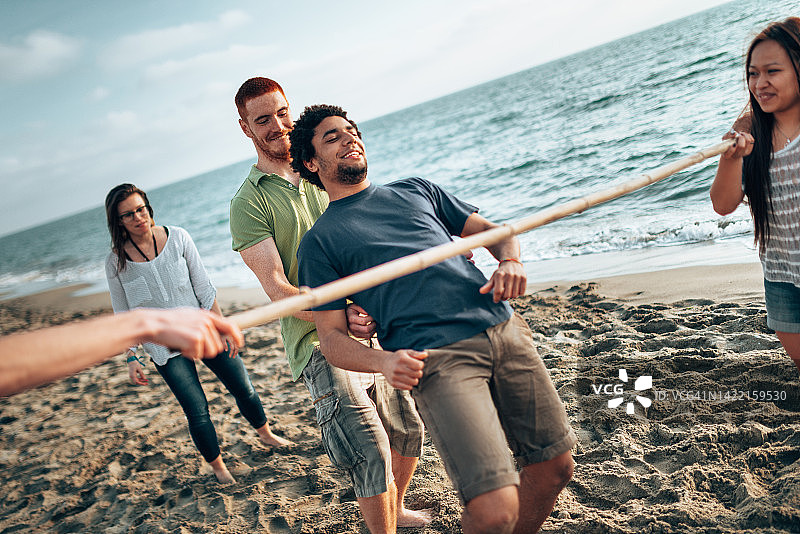 多元文化朋友在海滩玩 limbo 游戏图片素材
