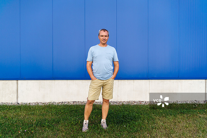 蓝色背景墙上的中年白人男子全身像图片素材