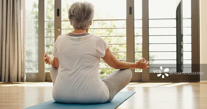 老年妇女在家中禅修，寻求精神平衡与健康图片素材