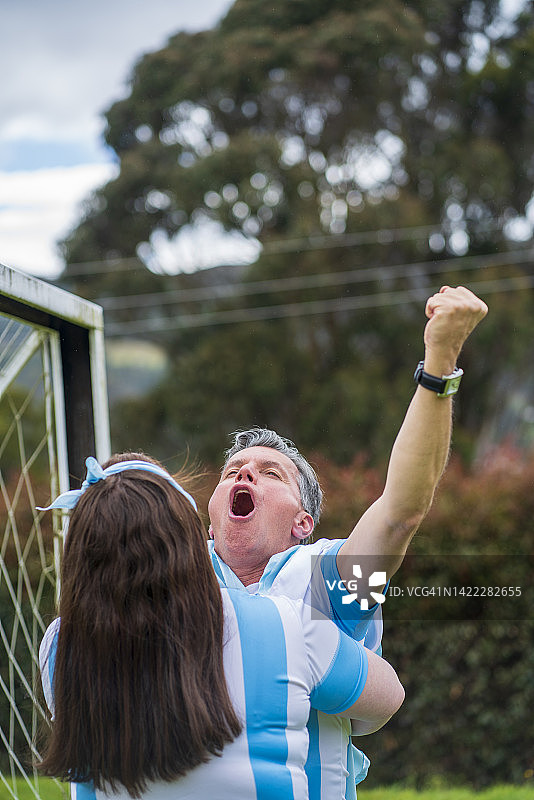 两名阿根廷足球队的球迷在球场草地上庆祝一个伟大的进球图片素材