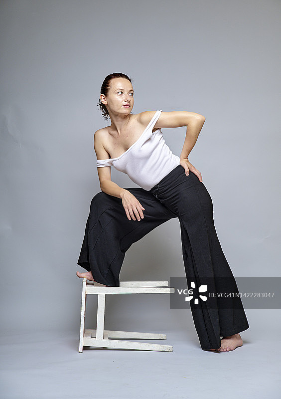 穿着黑色宽松裤在工作室摆姿势的红发女子图片素材