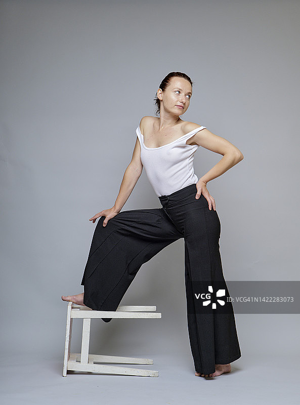 穿着黑色宽松裤在工作室摆姿势的红发女子图片素材