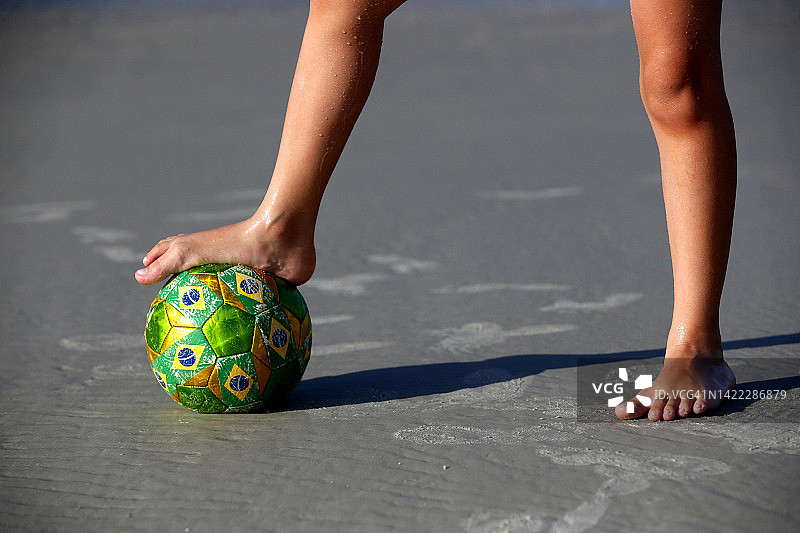 男孩在巴西海滩上玩足球图片素材