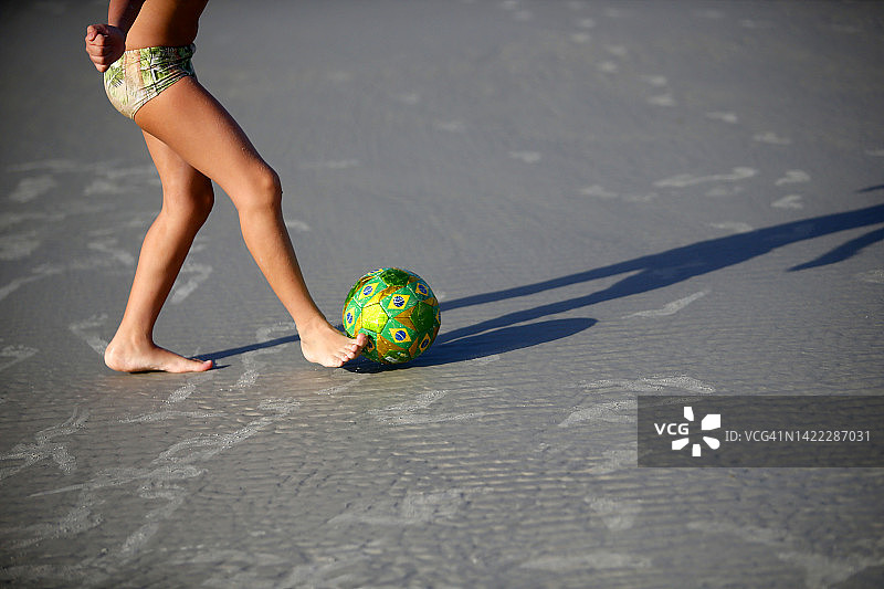男孩在巴西海滩上玩足球图片素材