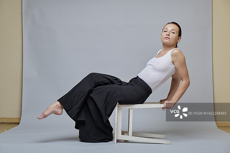 坐在凳子上，穿着宽松裤子的红发女人图片素材