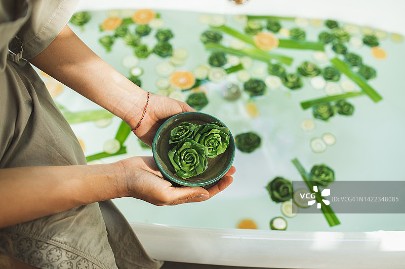 女人手捧装有天然沐浴材料和装饰品的碗图片素材