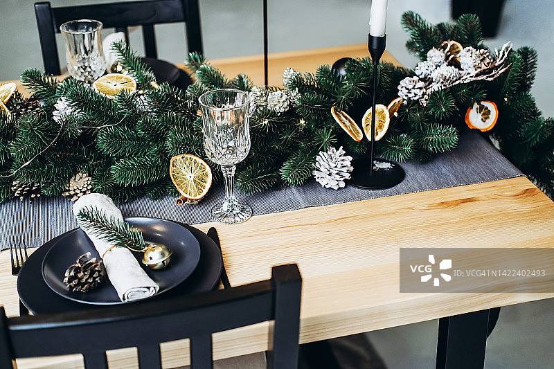 节日餐桌，有冷杉、松果、蜡烛、盘子和玻璃杯。图片素材