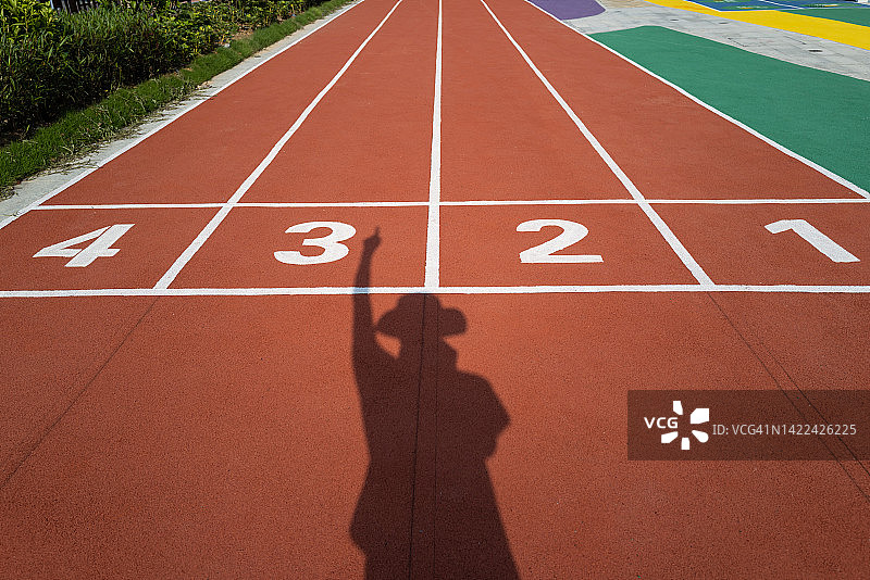 操场跑道上数字前的人的投影（做出向前的手势）图片素材
