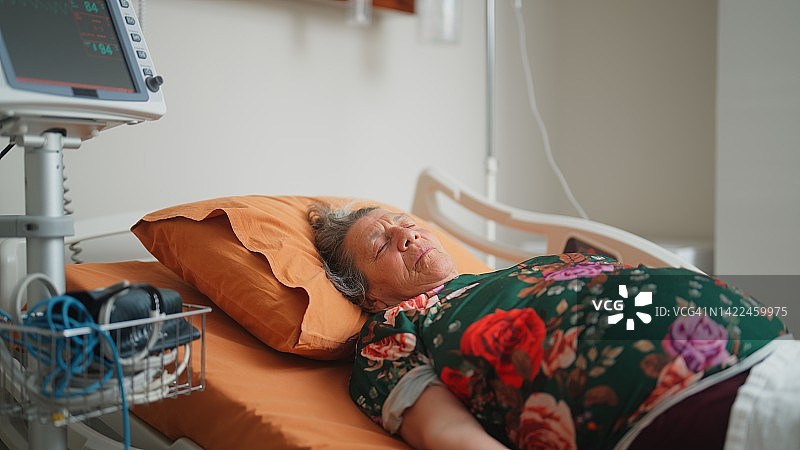 年长成人女性患者在医院接受治疗时于病床上休息图片素材