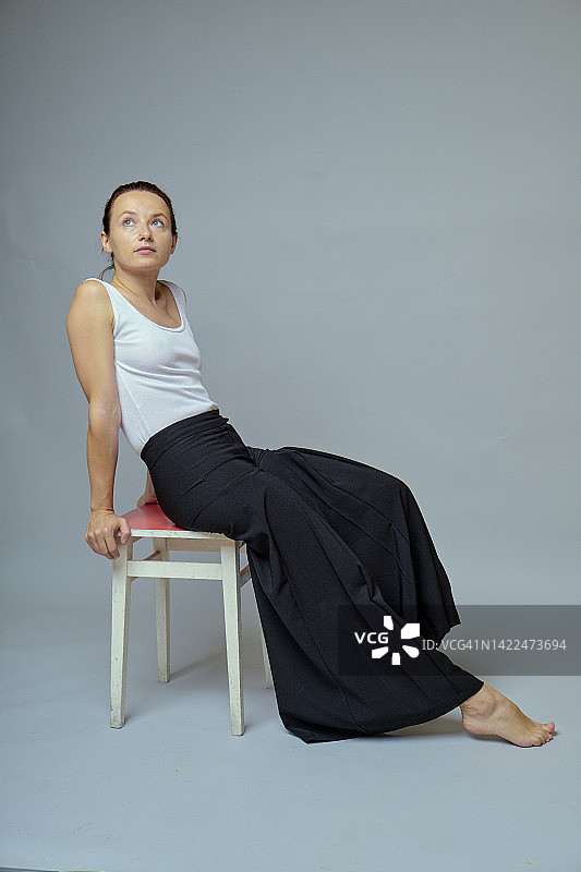 坐在凳子上，穿着宽松裤子的红发女人图片素材