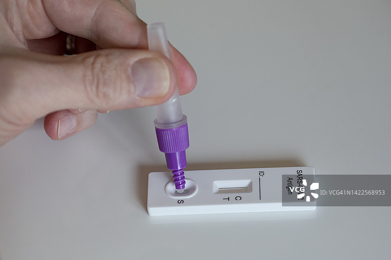 男子使用家用新冠病毒检测试剂盒的特写镜头图片素材