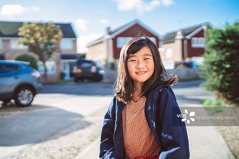 在阳光明媚的街区漫步时对着镜头快乐微笑的可爱女孩图片素材