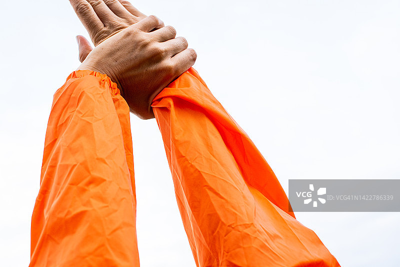 伸展手臂，橙色雨衣，白色背景图片素材
