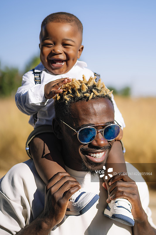 爸爸和宝宝儿子在他的肩膀上玩耍图片素材