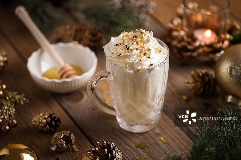 圣诞热巧克力蛋奶酒，玻璃杯装，顶部有搅打奶油和坚果图片素材